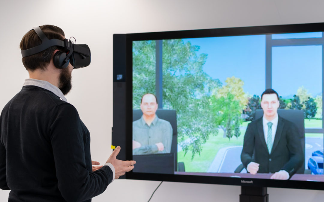 Ein Mann mit VR-Brille nutzt die Anwendung. Auf einem Bildschirm sieht man die virtuellen Verhandlungspartner. Bildquelle: Gerardo José Mouthron Caró