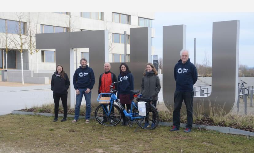 5 Menschen vor der Technischen Hochschule Ulm. Eine Frau hat ein Fahrrad